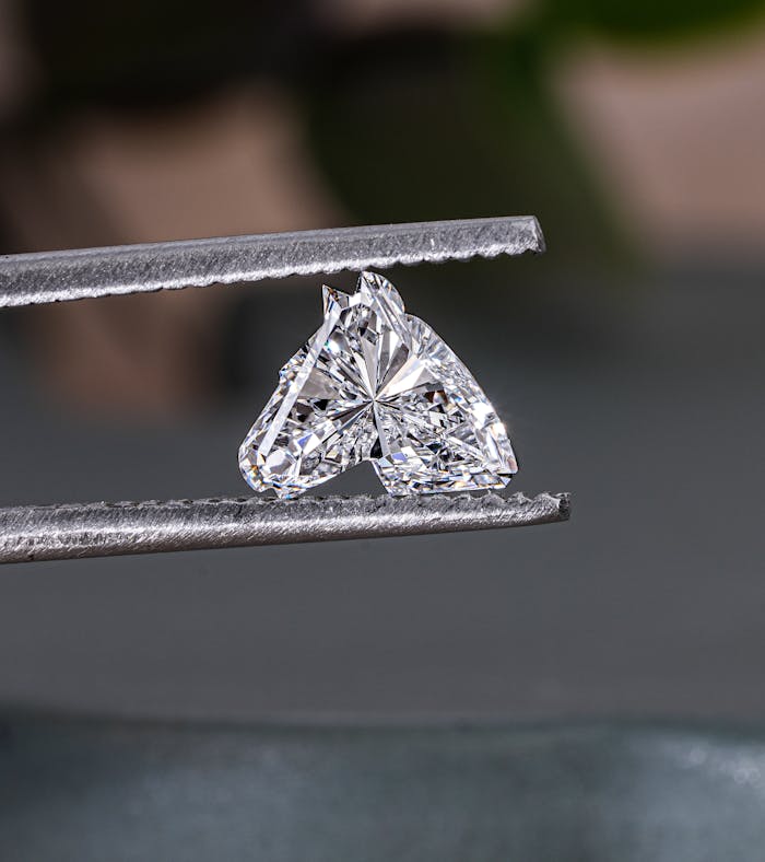 A stunning heart-shaped diamond captured in jeweler's tweezers, showcasing its brilliance and cut.