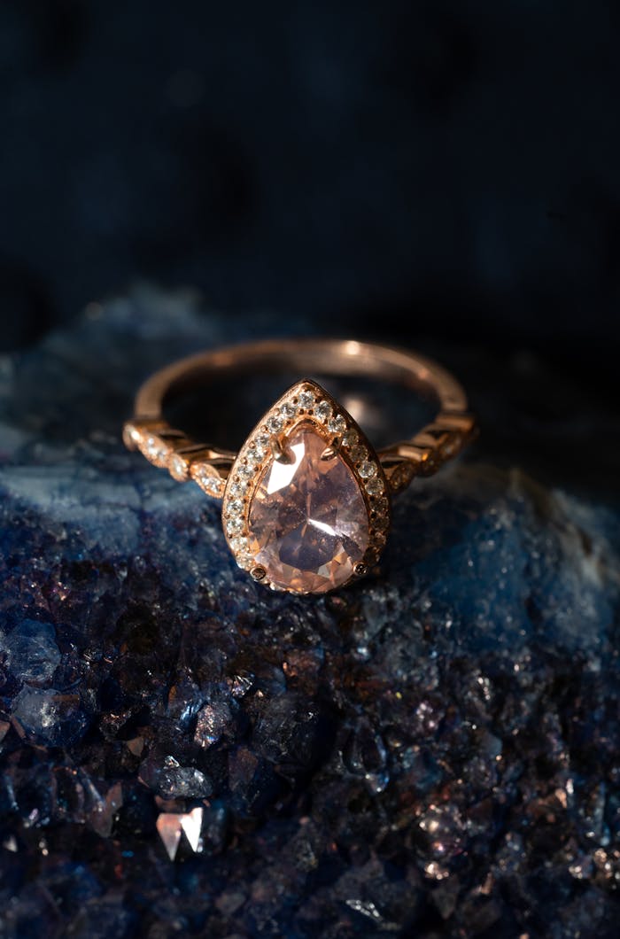 Close-up of a dazzling gold ring with a pear-shaped diamond set on a gemstone background.